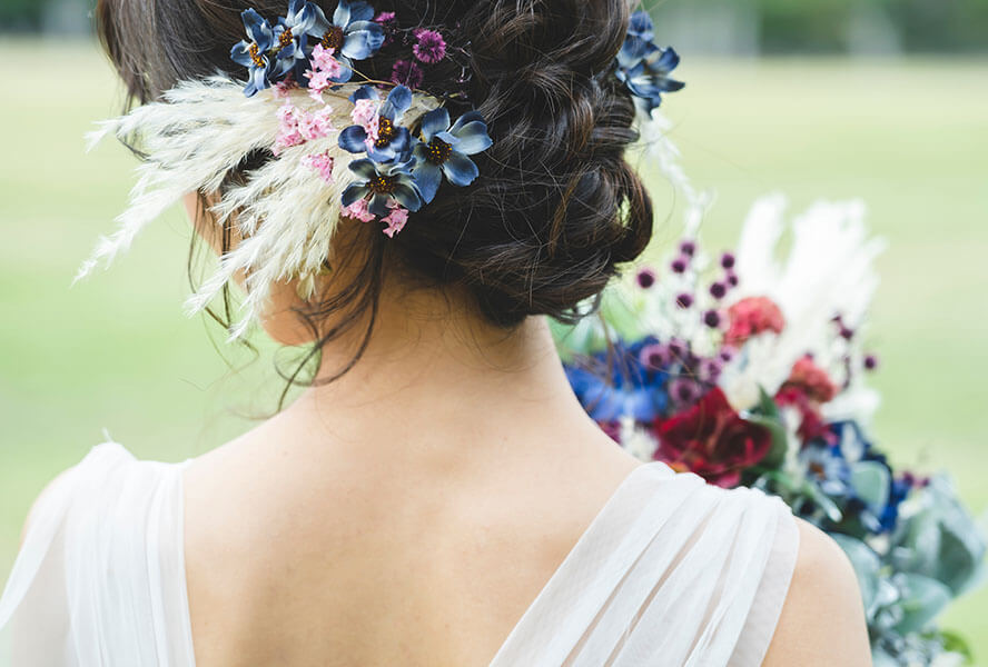 Braut hat einen bunten Blumenkranz in Ihrer Hochzeitsfrisur verarbeitet