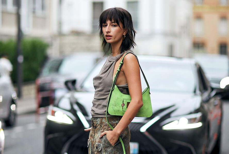 Schwarzhaarige Frau mit dem Trend-Haarschnitt Curly Wolf Cut in einem rockigen Outfit