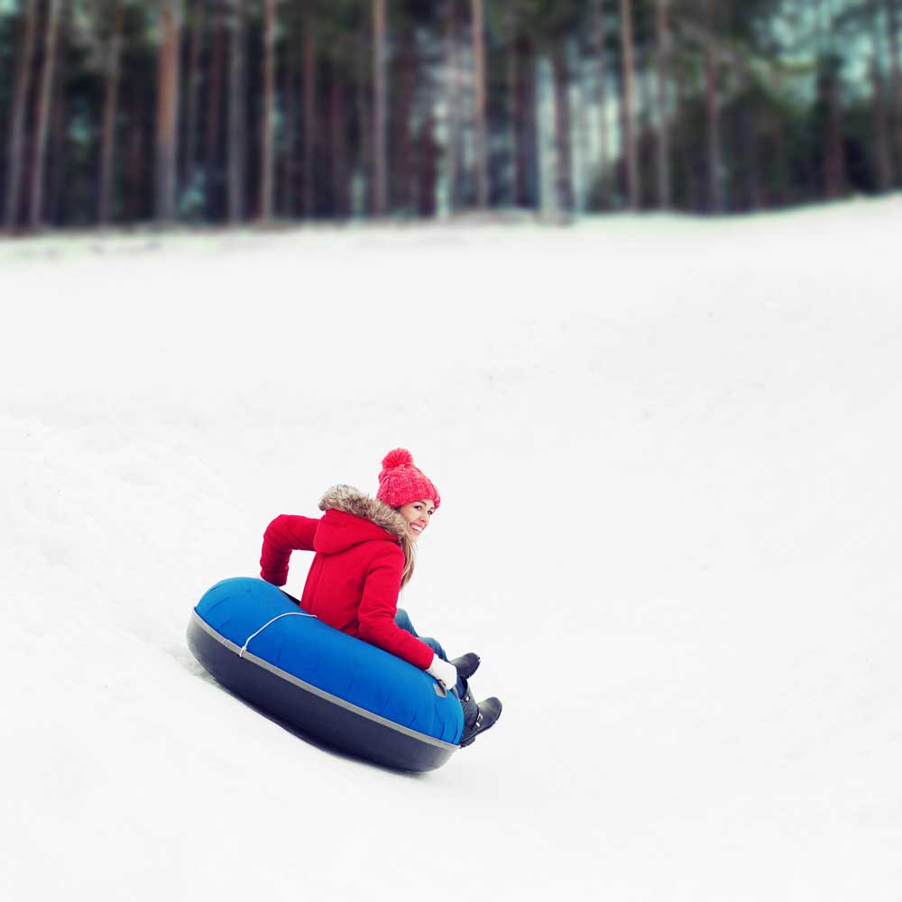 Snow-Tubing: Frau fährt auf einem Reifen durch den Schnee