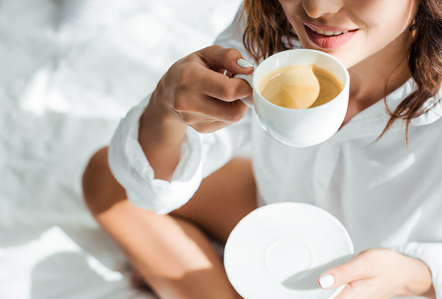 Frau trinkt einen Kaffee im Bett