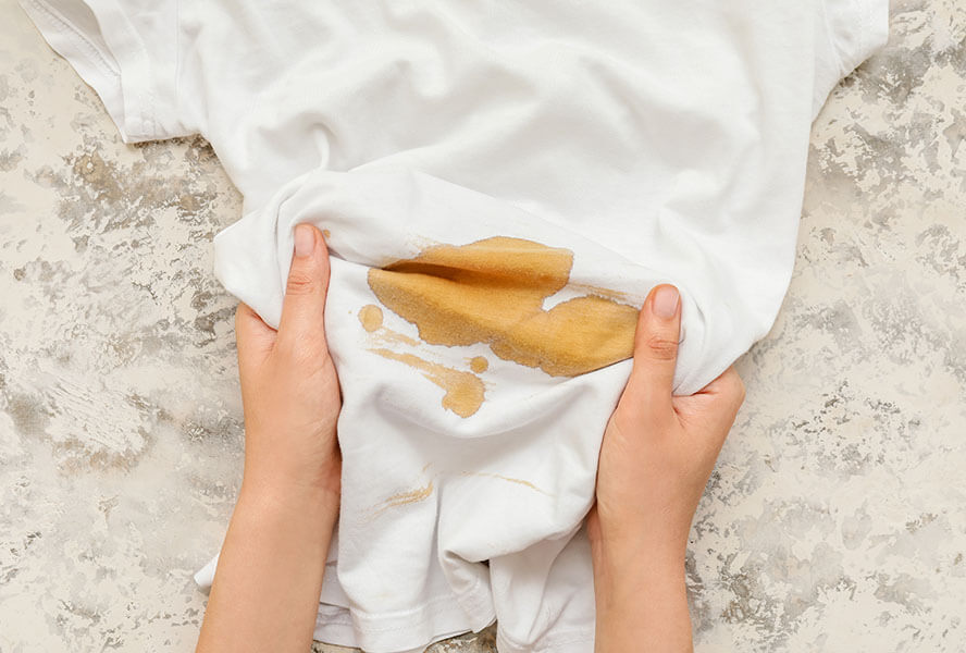 Weisses Kleidungsstück mit einem grossen Kaffeefleck darauf