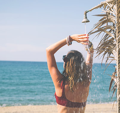 Frau wäscht sich am Strand mit Regenwasser