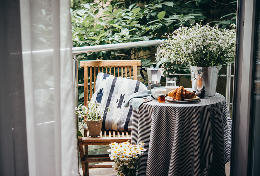 Balkon mit vielen Pflanzen und Balkonmöbeln