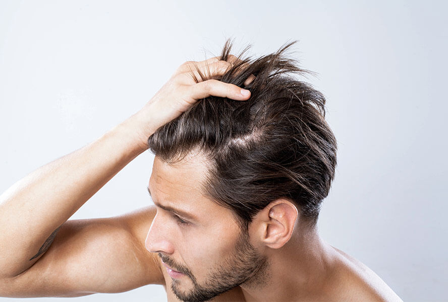 Mann mit glatten, braunen Haaren fährt sich durch die Haare