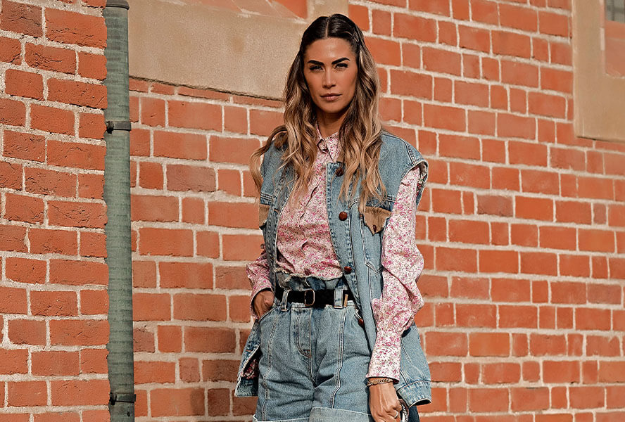 Frau mit Balayage Haaren in rosa Bluse und Jeansjacke