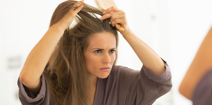 Frau die sich die Haare kämt mit einer fettigen Kopfhaut