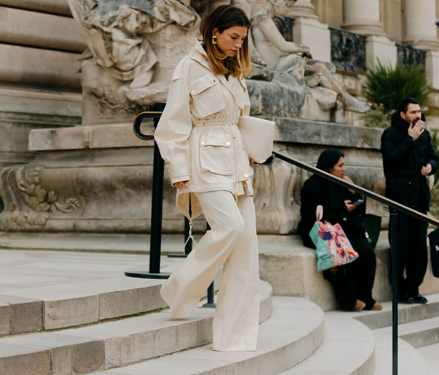 Frau in einem all-white-Look mit weisser Marlenehose und weisser Jacke