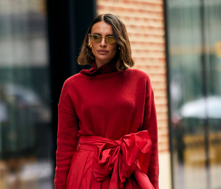 Frau mit welligem Bob in einem roten Outfit und Sonnenbrille