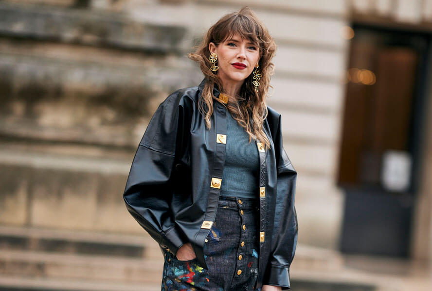 Frau in schwarzem Leder-Outfit mit goldenen Details trägt einen Soft Mullet bei langem Haar