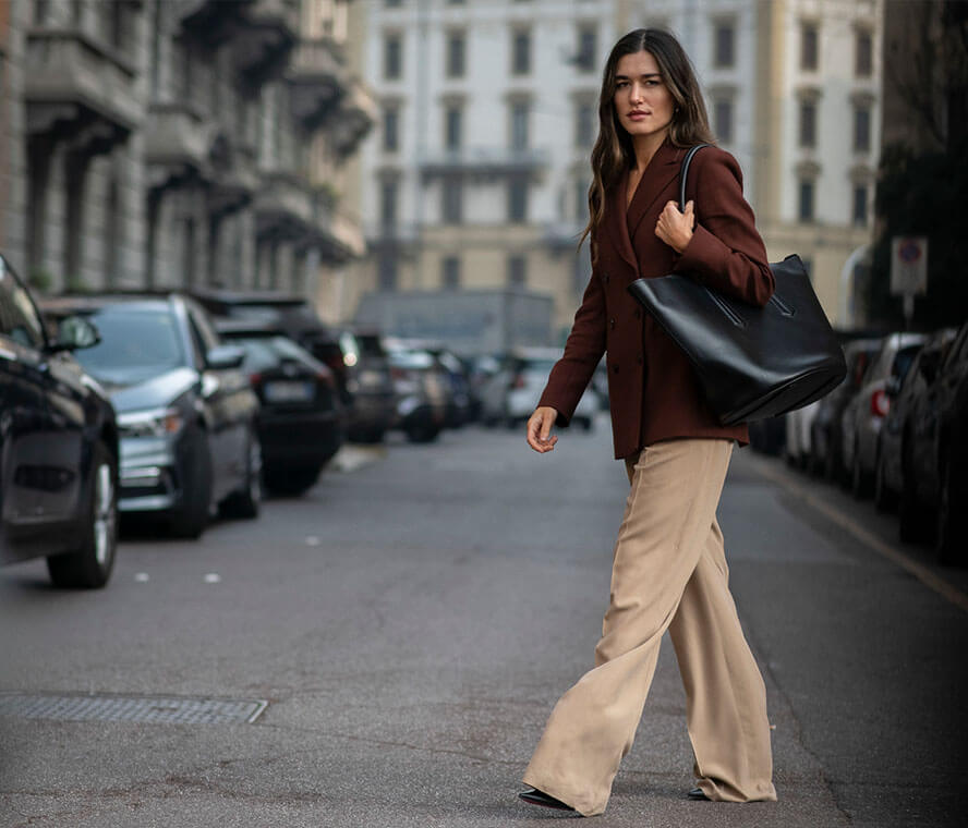 Grosse Frau trägt eine weite Hose in Beige mit rostrotem Blazer dazu